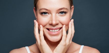 Woman smiling with both hands on the face