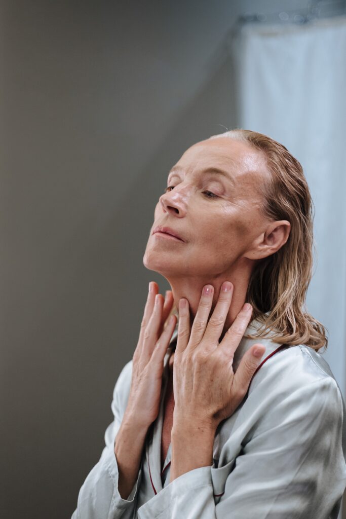 Woman looking at herself and checking her skin. Image illustrate facelift procedure