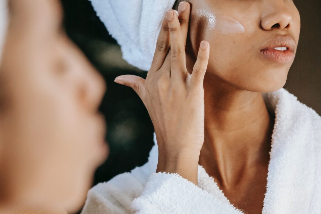 Woman looking in the mirror and passing a facial cream on her face