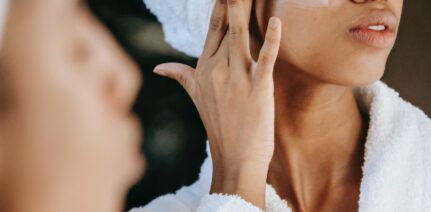 Woman looking in the mirror and passing a facial cream on her face