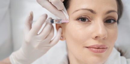 Close up of doctor cosmetologist in sterile gloves making contour plastic injection into female face