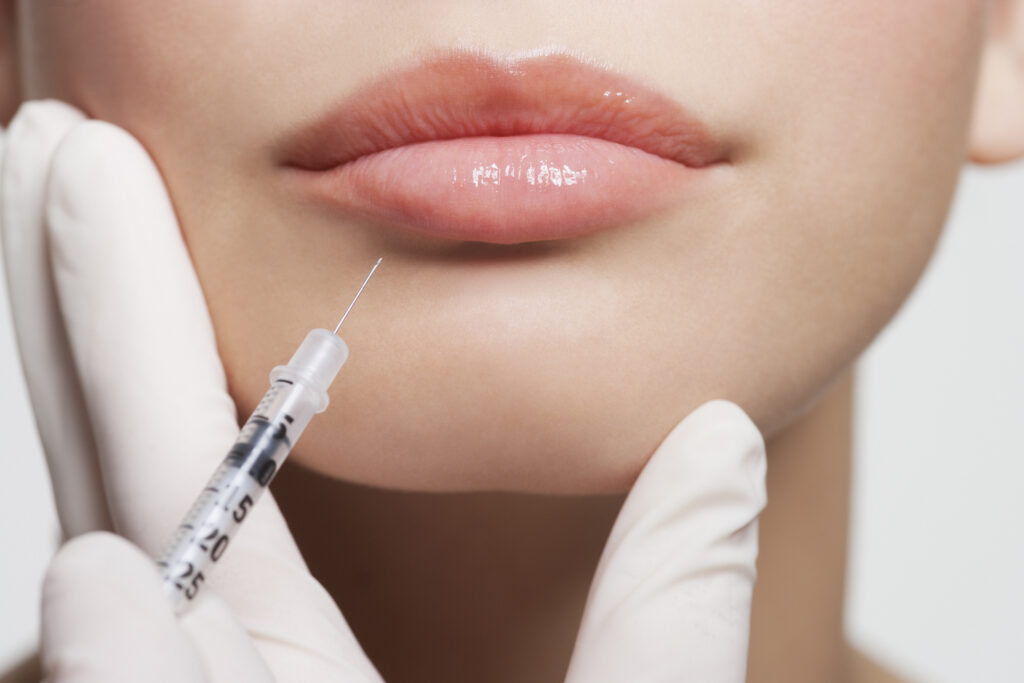 Close up of woman receiving botox injection in lips