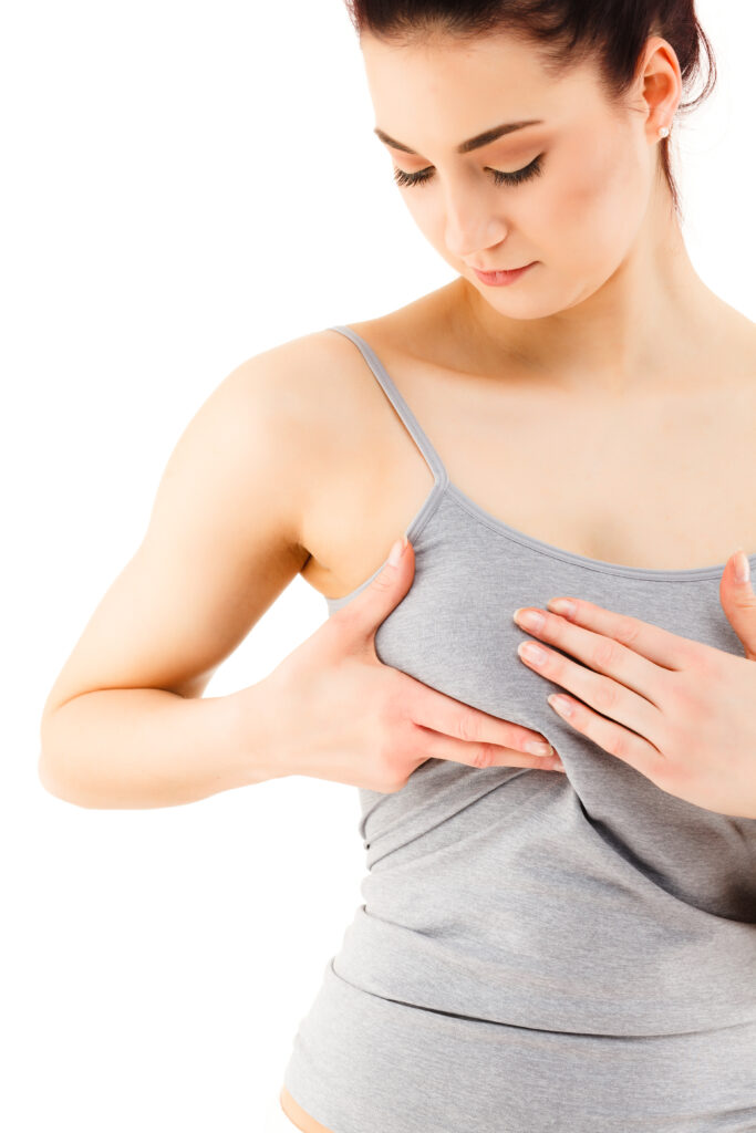 Woman examining her breast on white background.